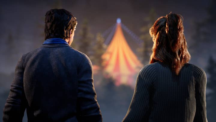 Two people look out into the distance, where a circus tent glows in the darkness